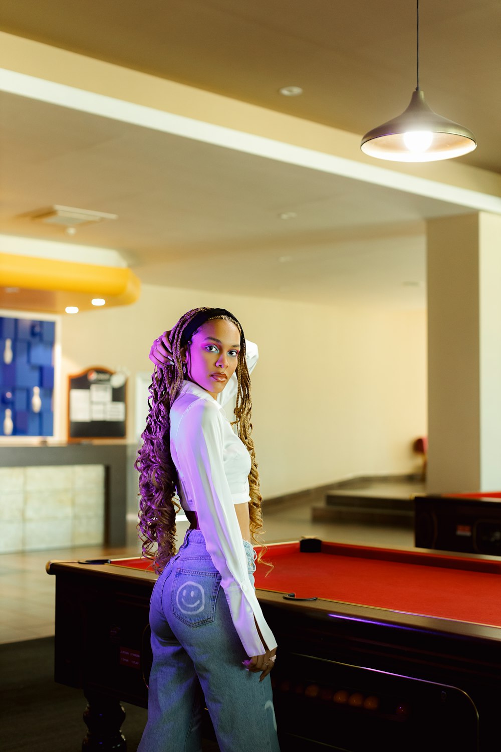 a young girl standing in front of a pool table