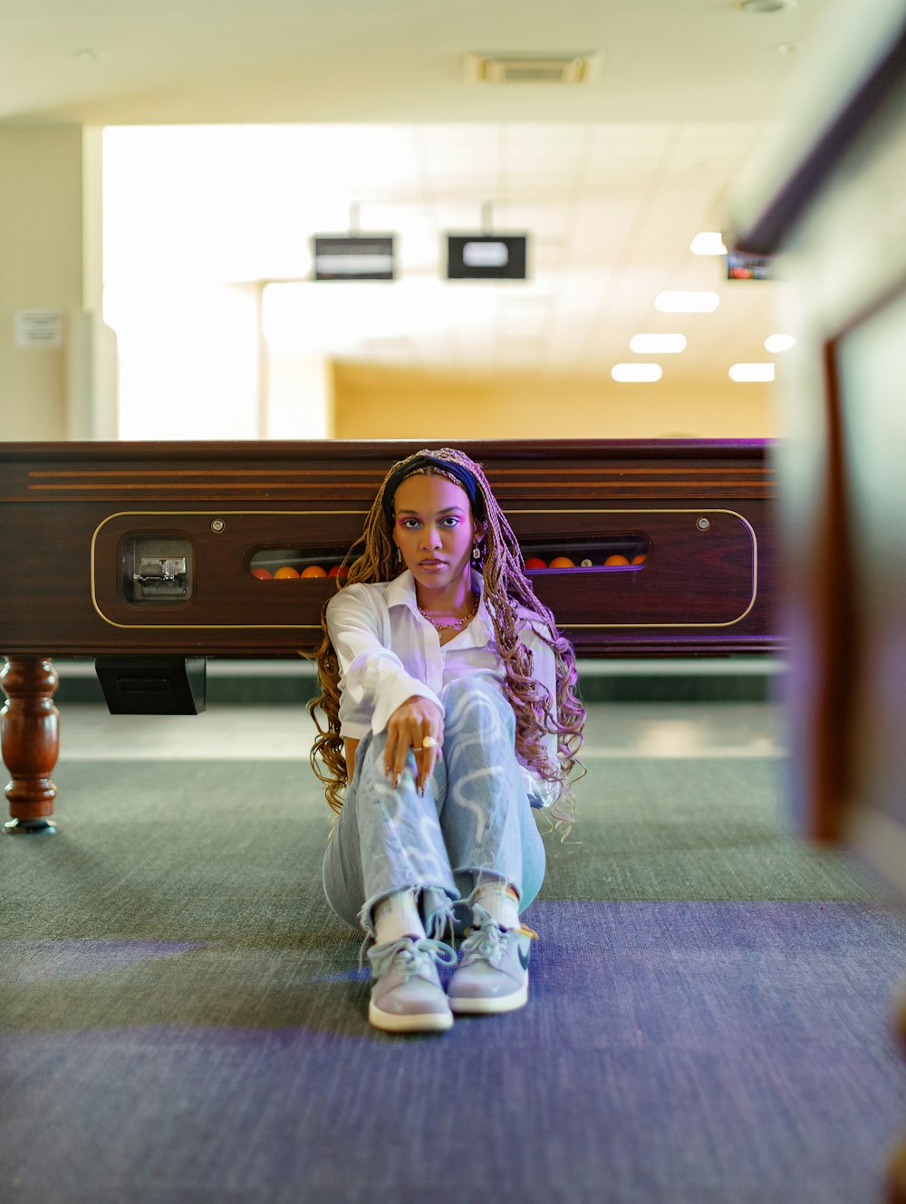 a woman sitting on the ground in front of a bench