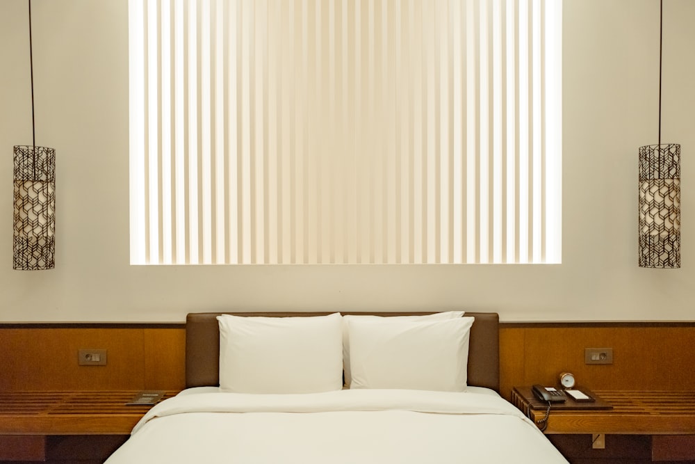 a bed with white sheets and pillows in a room