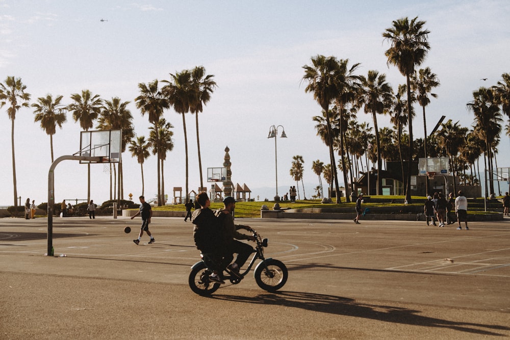 a man riding a motorcycle down a street next to palm trees