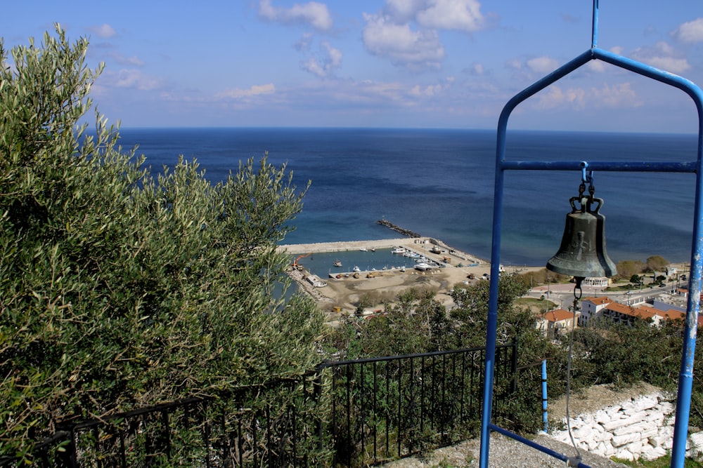 a bell on a metal pole next to a body of water