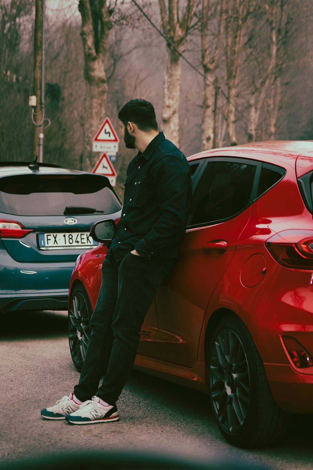 a man sitting on the hood of a red car