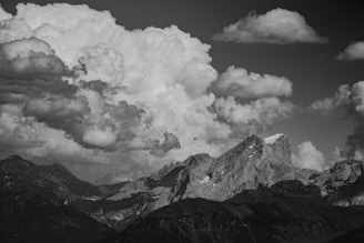 A dramatic black and white landscape of rugged mountains under a stormy sky.