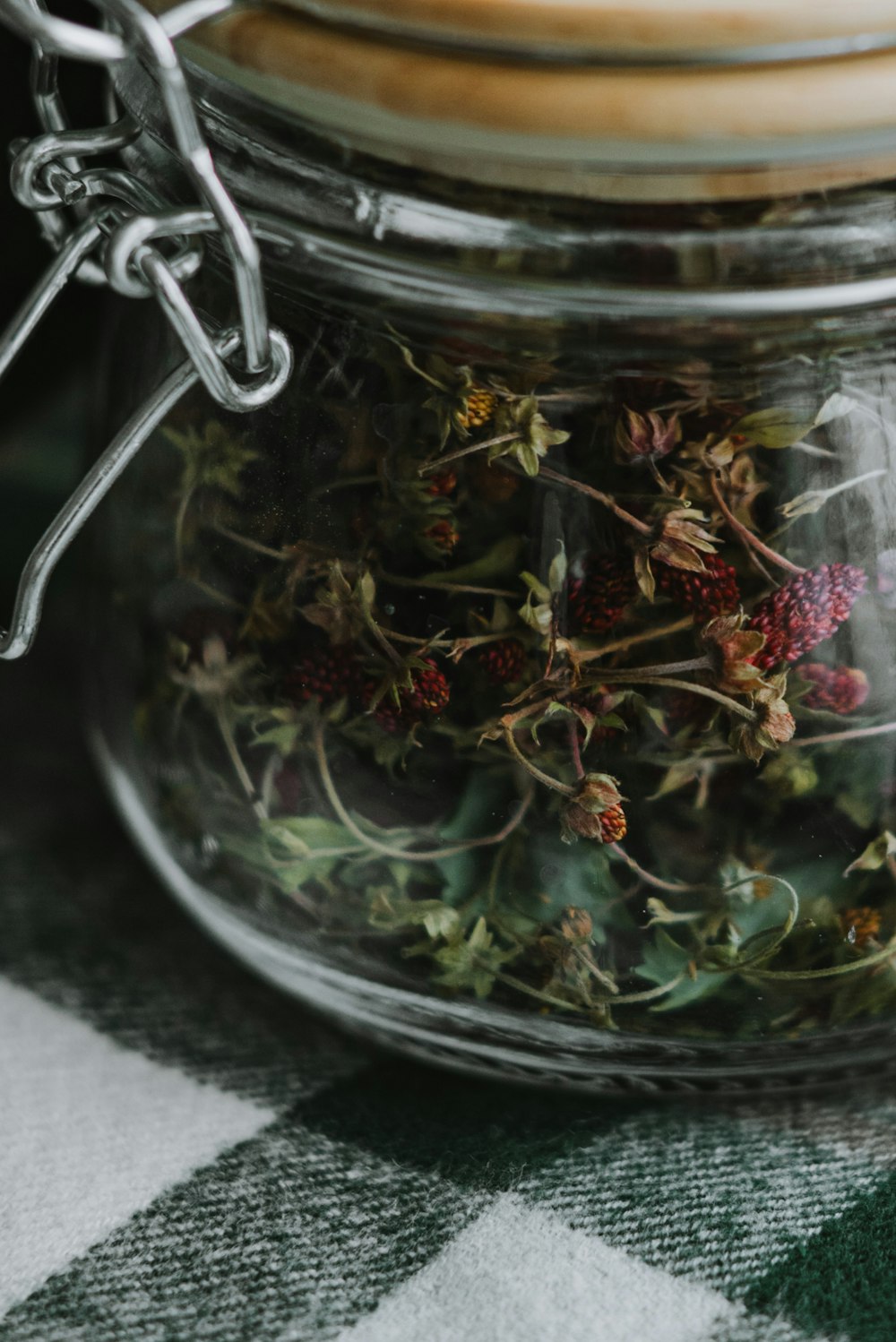 a jar filled with dried flowers on top of a checkered table cloth