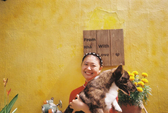 A cozy corner with a smiling volunteer cuddling a happy dog in a sunny garden.