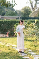 Softly lit photo of a woman in a flowing peach dress holding a bouquet of wildflowers in a sunlit garden.