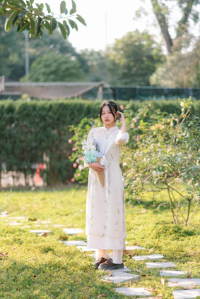 Elegant woman wearing a floral summer dress in a sunlit garden