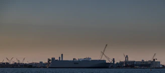 Modern shipyard with cranes and ships under construction at sunset.