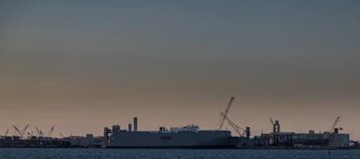 Modern shipyard with cranes and ships under construction at sunset.