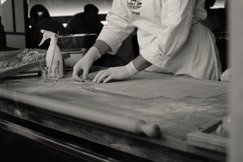 a man in a chef's uniform waxing a piece of paper on a
