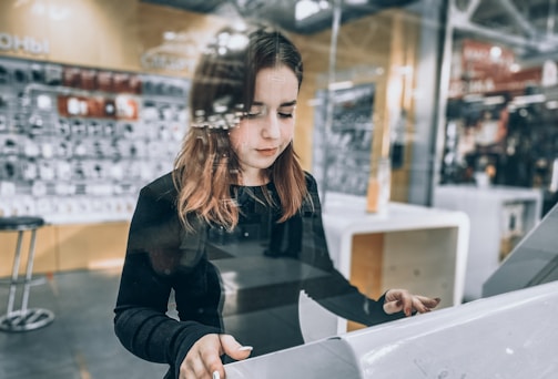 A smiling young woman selecting designs on a touchscreen kiosk.