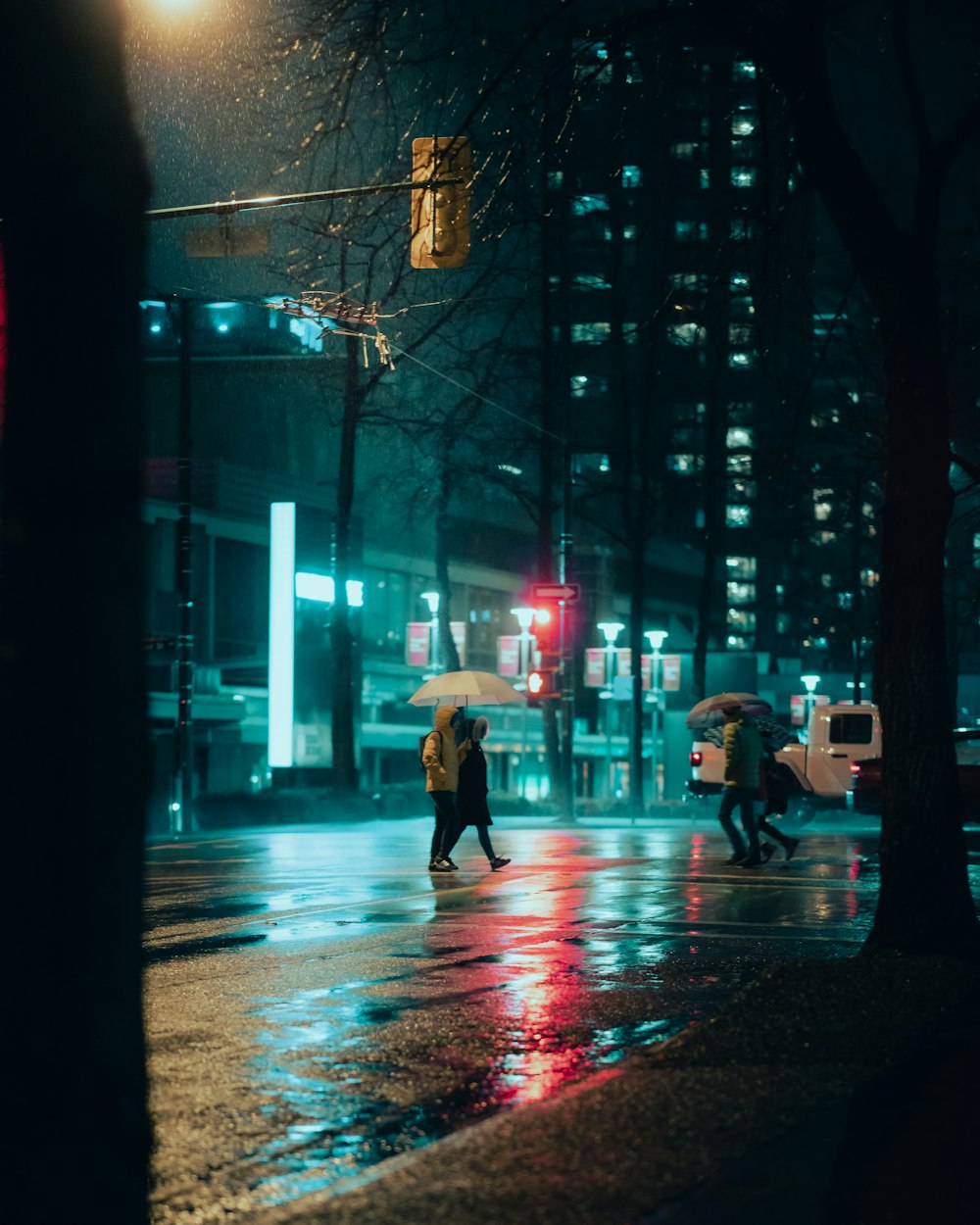 a couple of people walking across a street at night