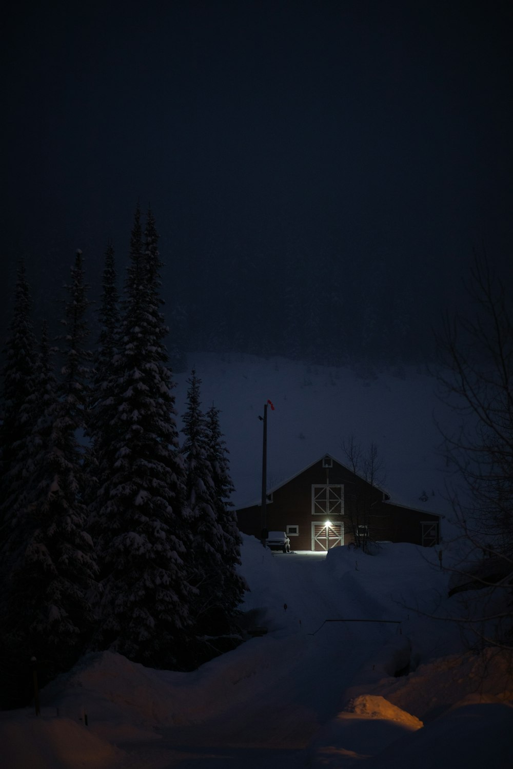 a cabin is lit up at night in the snow