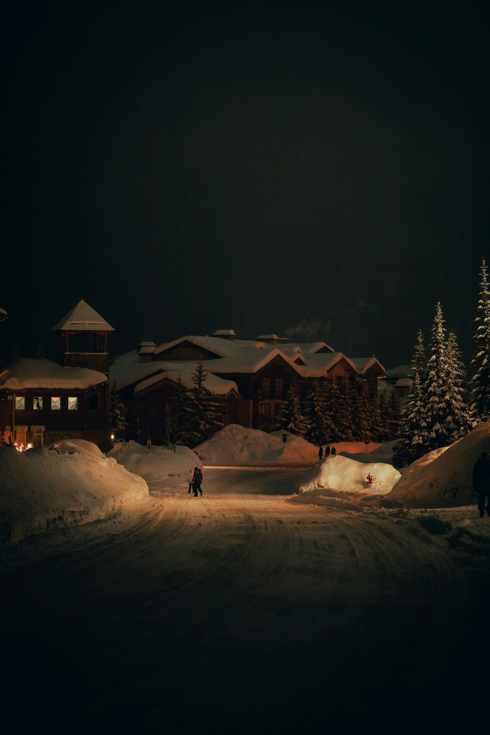 a couple of people walking down a snow covered road