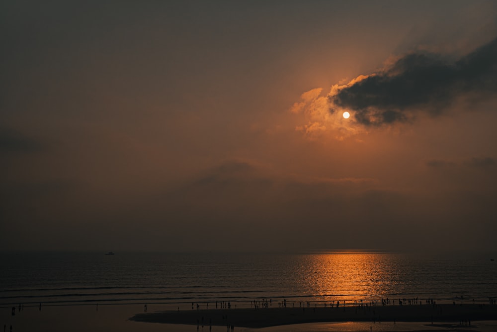 the sun is setting over the ocean on a cloudy day