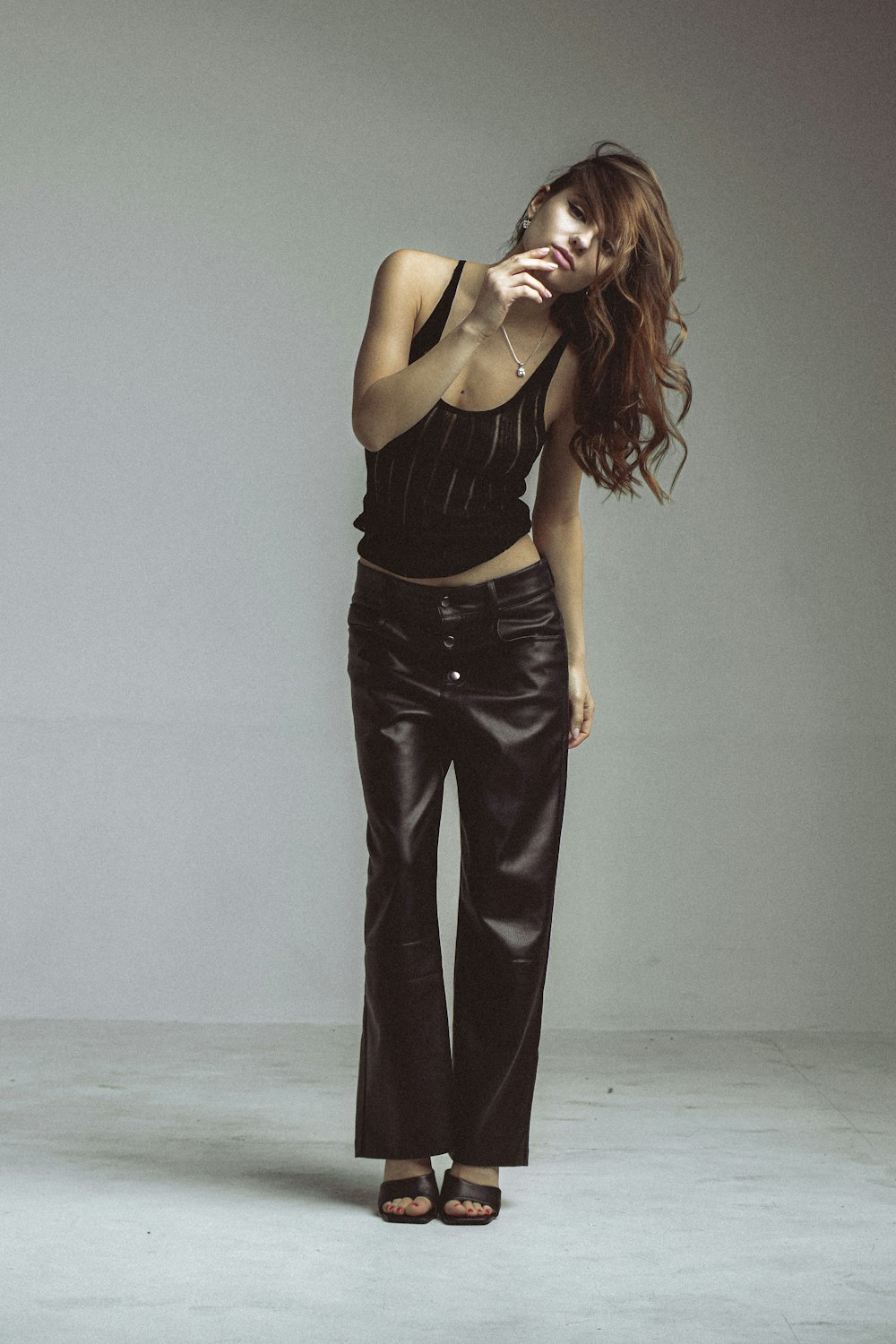 a woman posing in a black top and leather pants