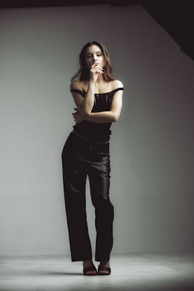 A confident woman wearing nude-toned shapewear, standing gracefully in a softly lit minimalist room.