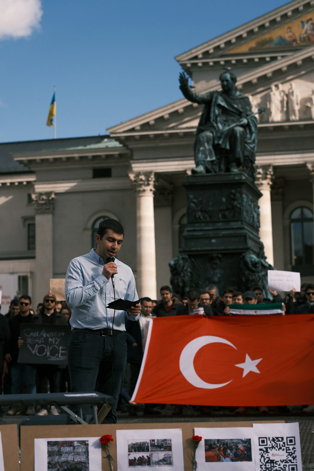 a man speaking into a microphone in front of a building