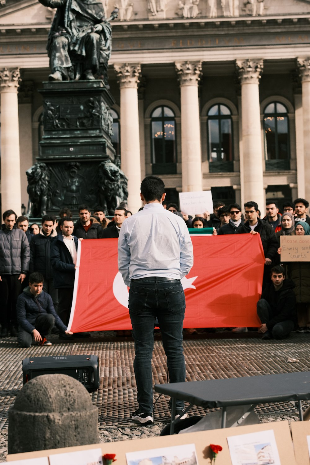 Un hombre parado frente a una gran bandera roja