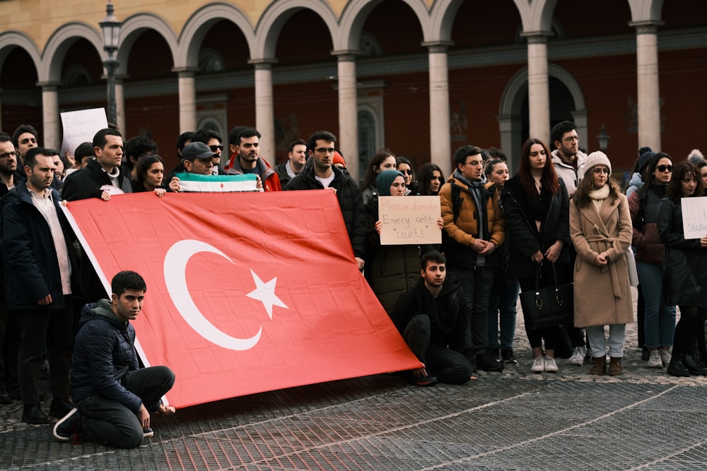 a group of people standing around a large turkey flag