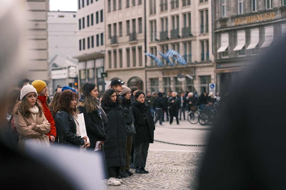 Un grupo de personas de pie en una calle junto a edificios altos