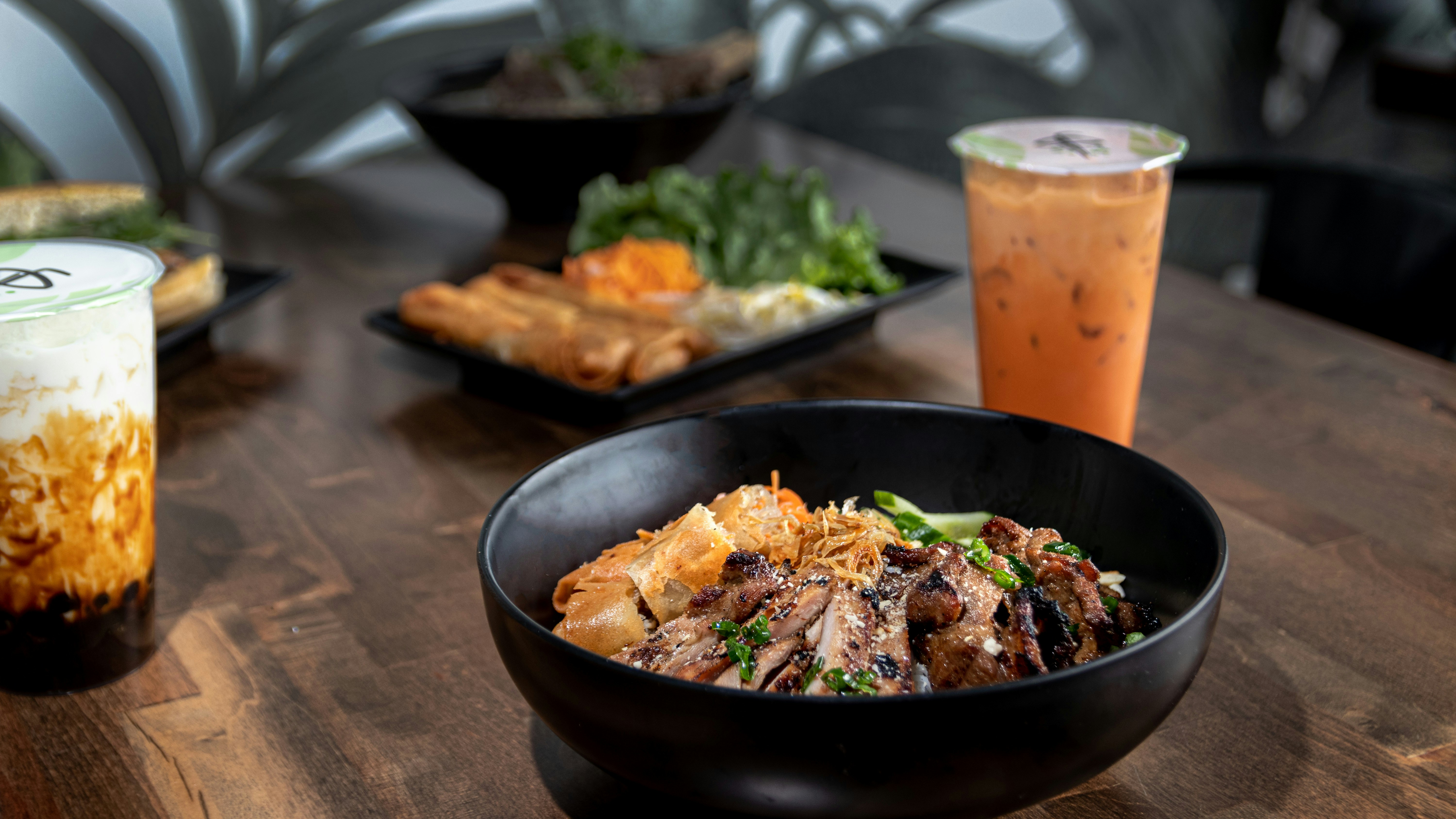 Black bowl of noodles with Thai iced tea