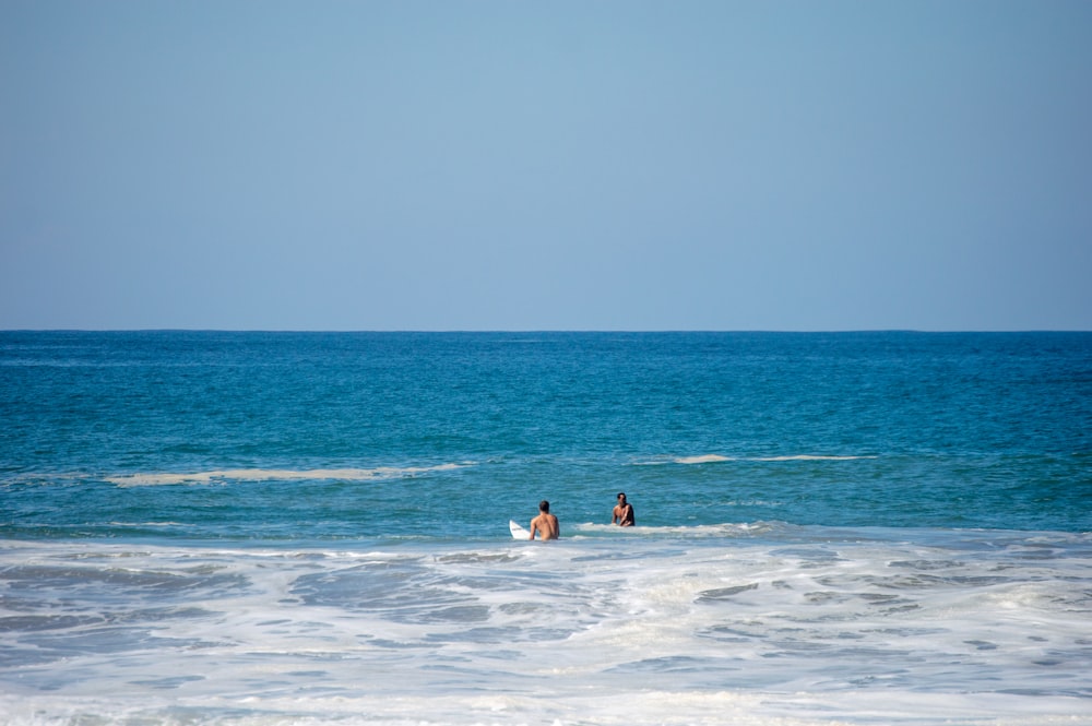 a couple of people riding surfboards on top of a wave