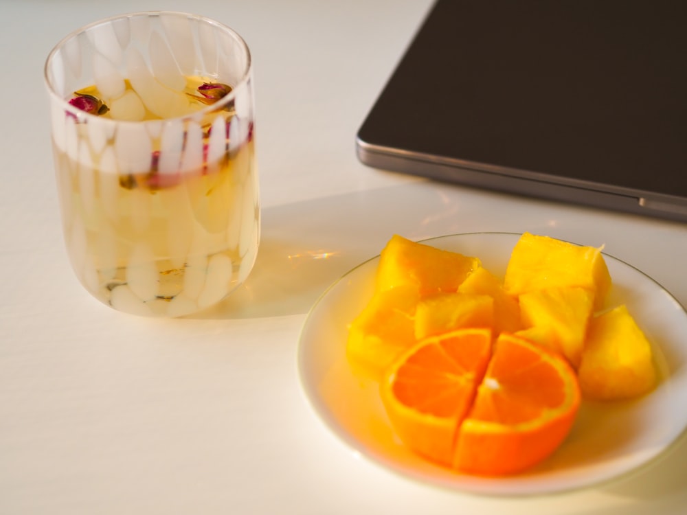 a plate of sliced oranges next to a glass of water