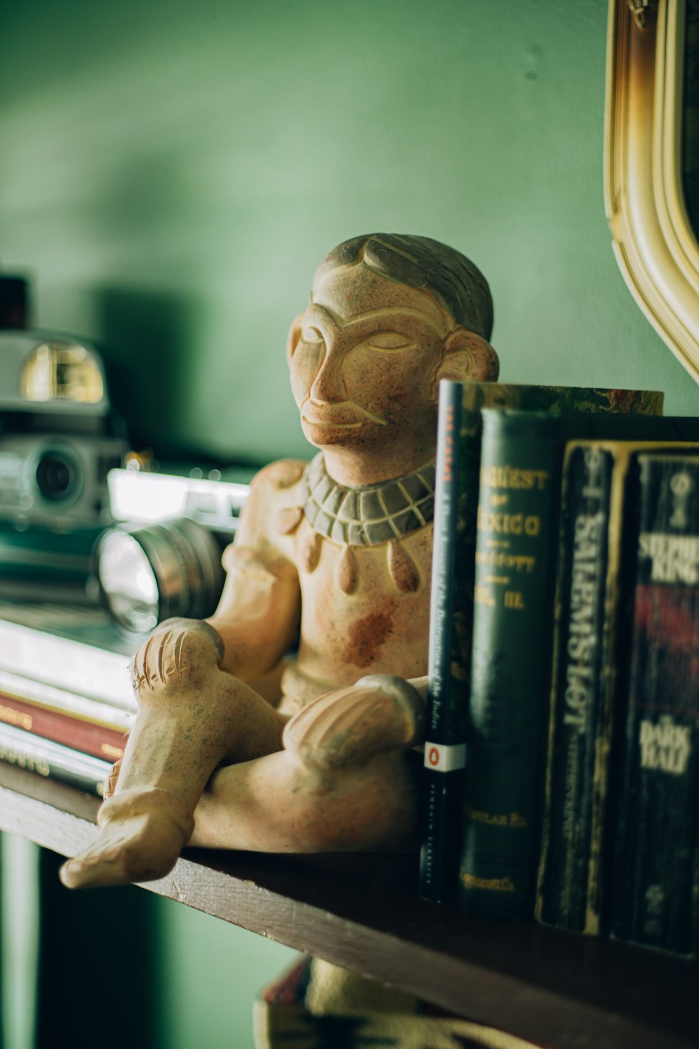 a statue of a person sitting on top of a shelf