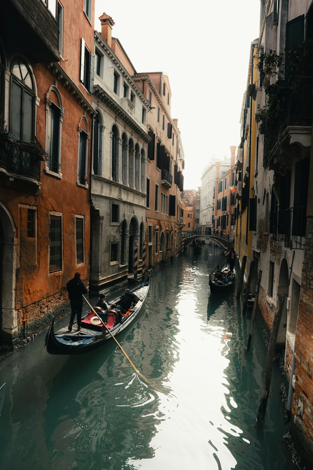 a man is rowing a boat down a narrow canal