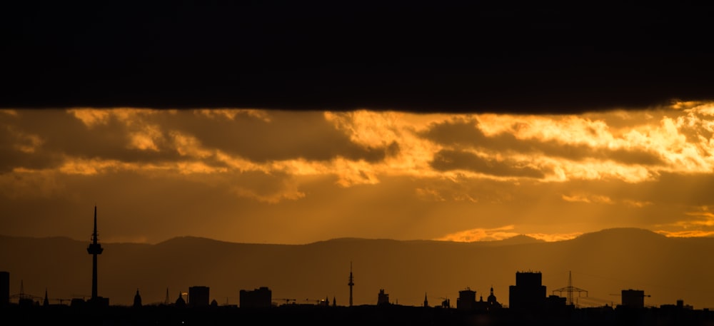 the sun is setting over a city with mountains in the background