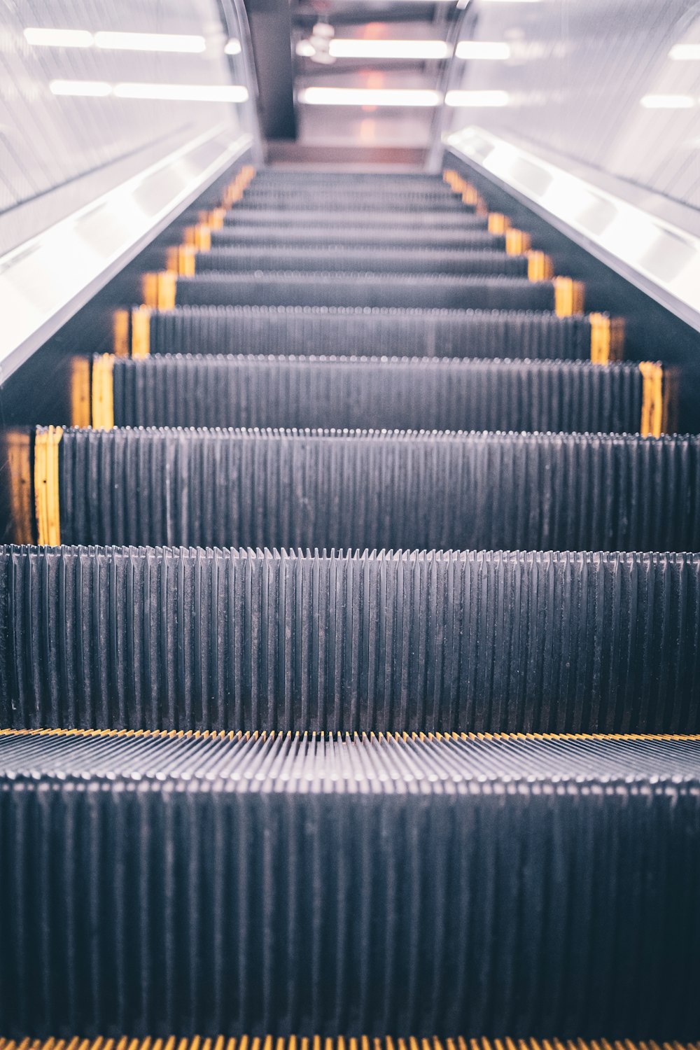 an escalator with yellow bars going down it