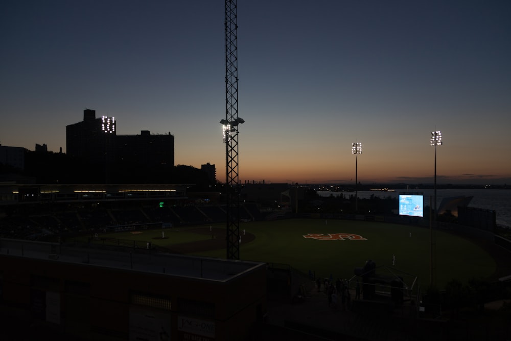 a baseball field at night with the sun setting