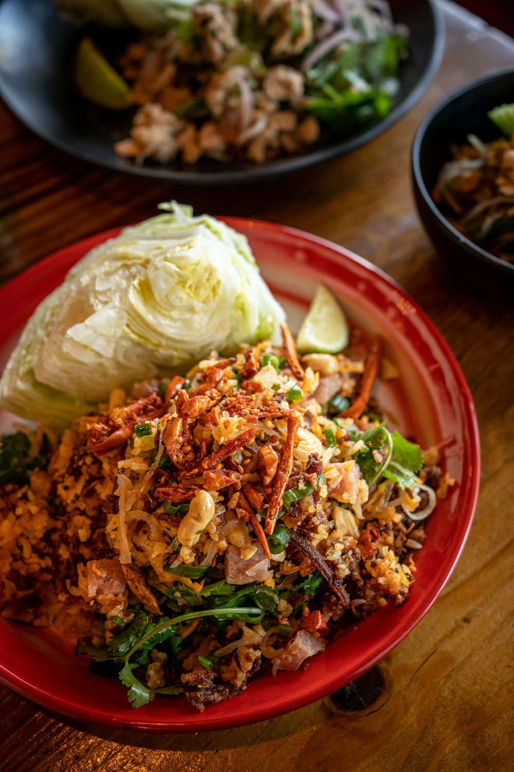 a red plate topped with lots of food on top of a wooden table