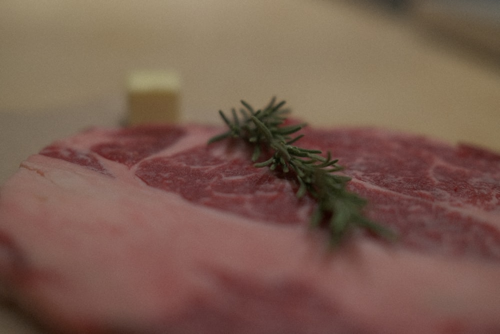 a piece of raw meat with a sprig of rosemary on top