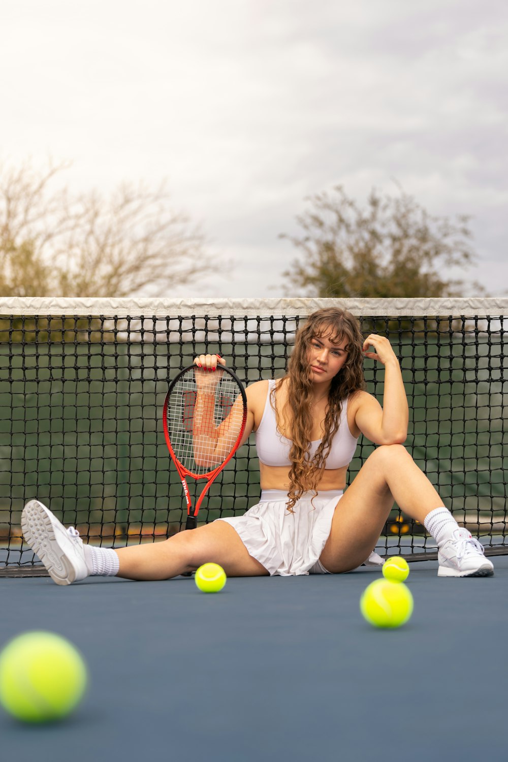 a woman sitting on a tennis court holding a tennis racquet