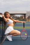 a beautiful young woman holding a tennis racquet on a tennis court