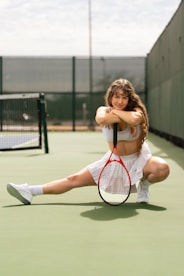 a woman sitting on a tennis court holding a racquet