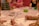 Children are seated around a table engaged in a painting activity. Each child holds a paintbrush, focusing on their artwork. A variety of colors and art supplies are scattered on the table, creating a lively and creative atmosphere.