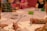 Children are seated around a table engaged in a painting activity. Each child holds a paintbrush, focusing on their artwork. A variety of colors and art supplies are scattered on the table, creating a lively and creative atmosphere.