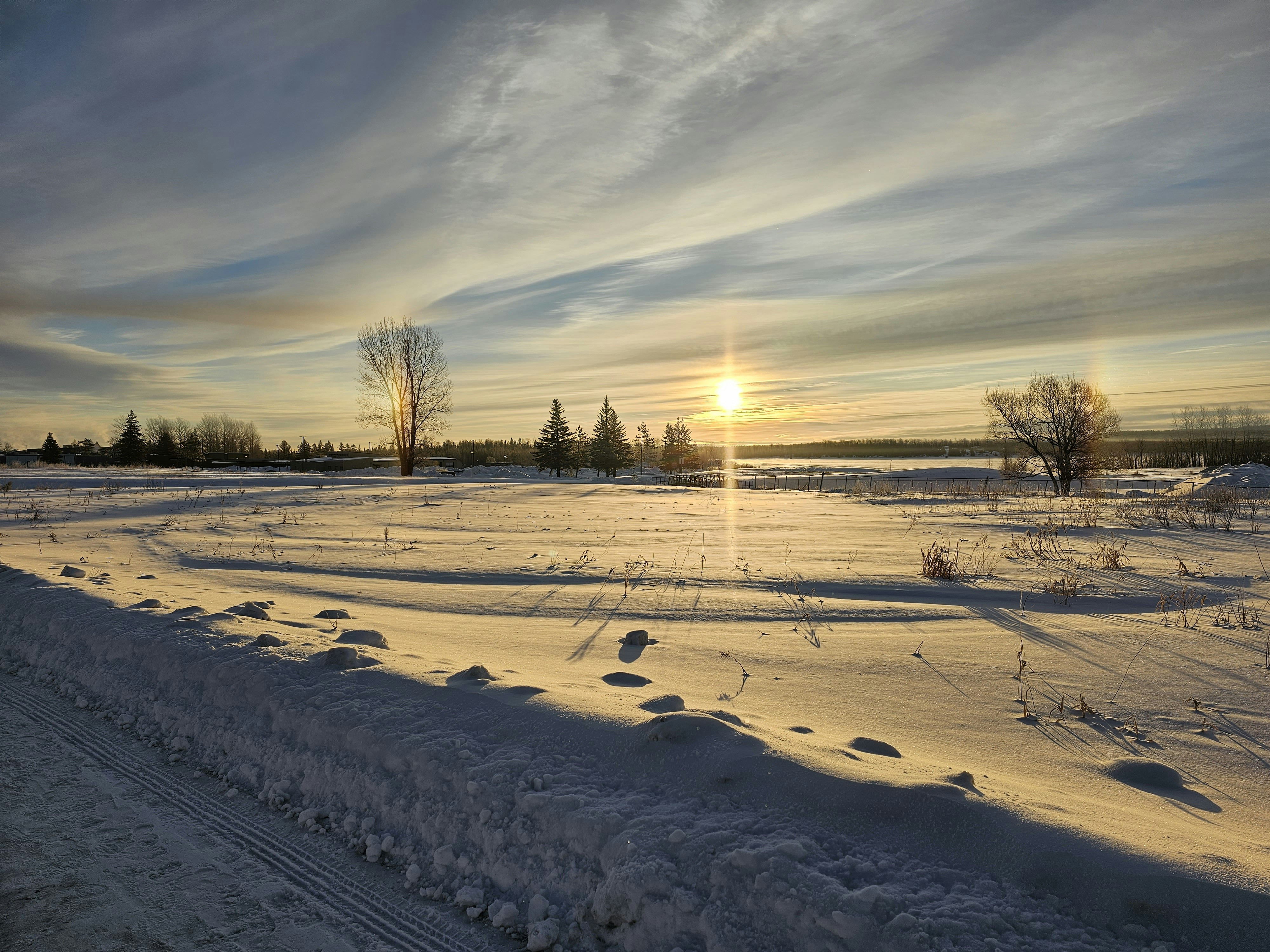 the sun is setting over a snowy field