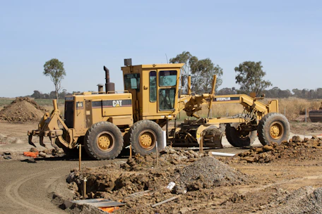 Heavy machinery grading a large commercial site surrounded by earth and construction materials.