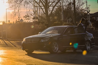 A friendly chauffeur opening the car door for a passenger at sunset.