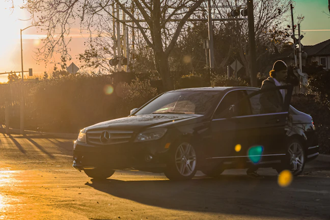 Chauffeur opening car door for a client outside a private jet under a golden sunset.