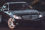 Sleek black Mercedes-Benz sedan parked under soft golden lighting, reflecting elegance.