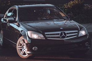 Sleek black Mercedes-Benz sedan parked under soft golden lighting, reflecting elegance.
