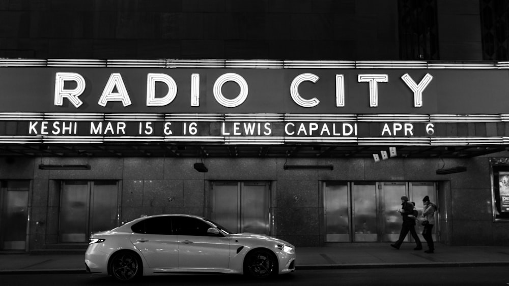 a white car parked in front of a radio city sign
