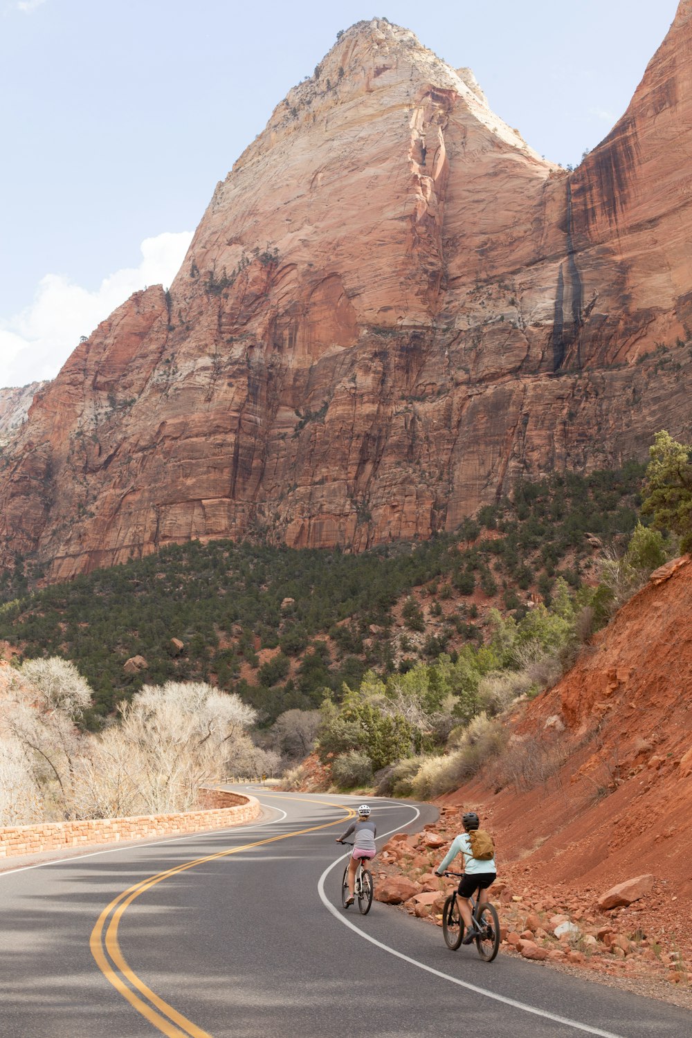 a couple of people riding bikes down a curvy road