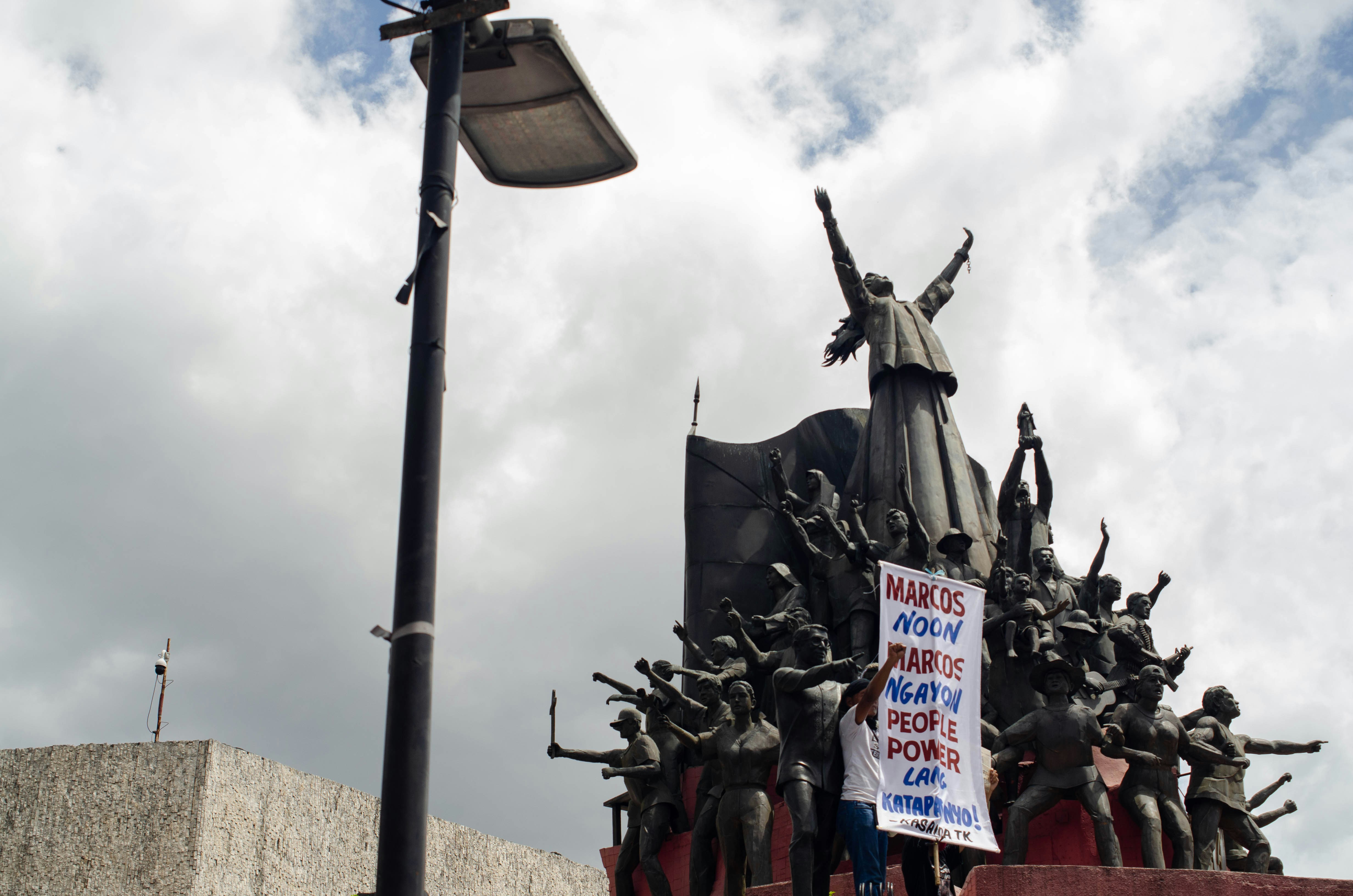 a protest sign is displayed in front of a statue