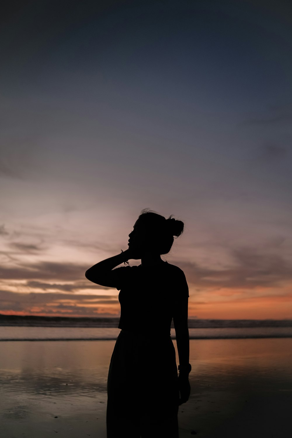 uma mulher em pé no topo de uma praia ao lado do oceano